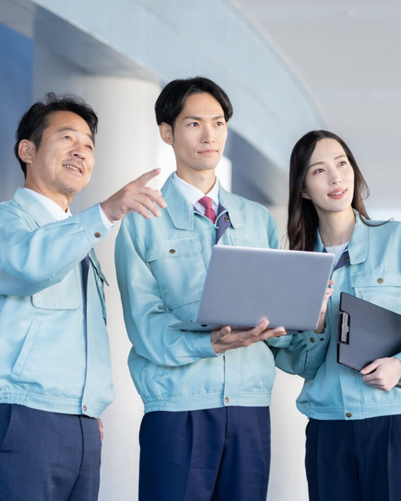 作業服を着たスタッフがパソコンを見ながら打ち合わせをしている様子